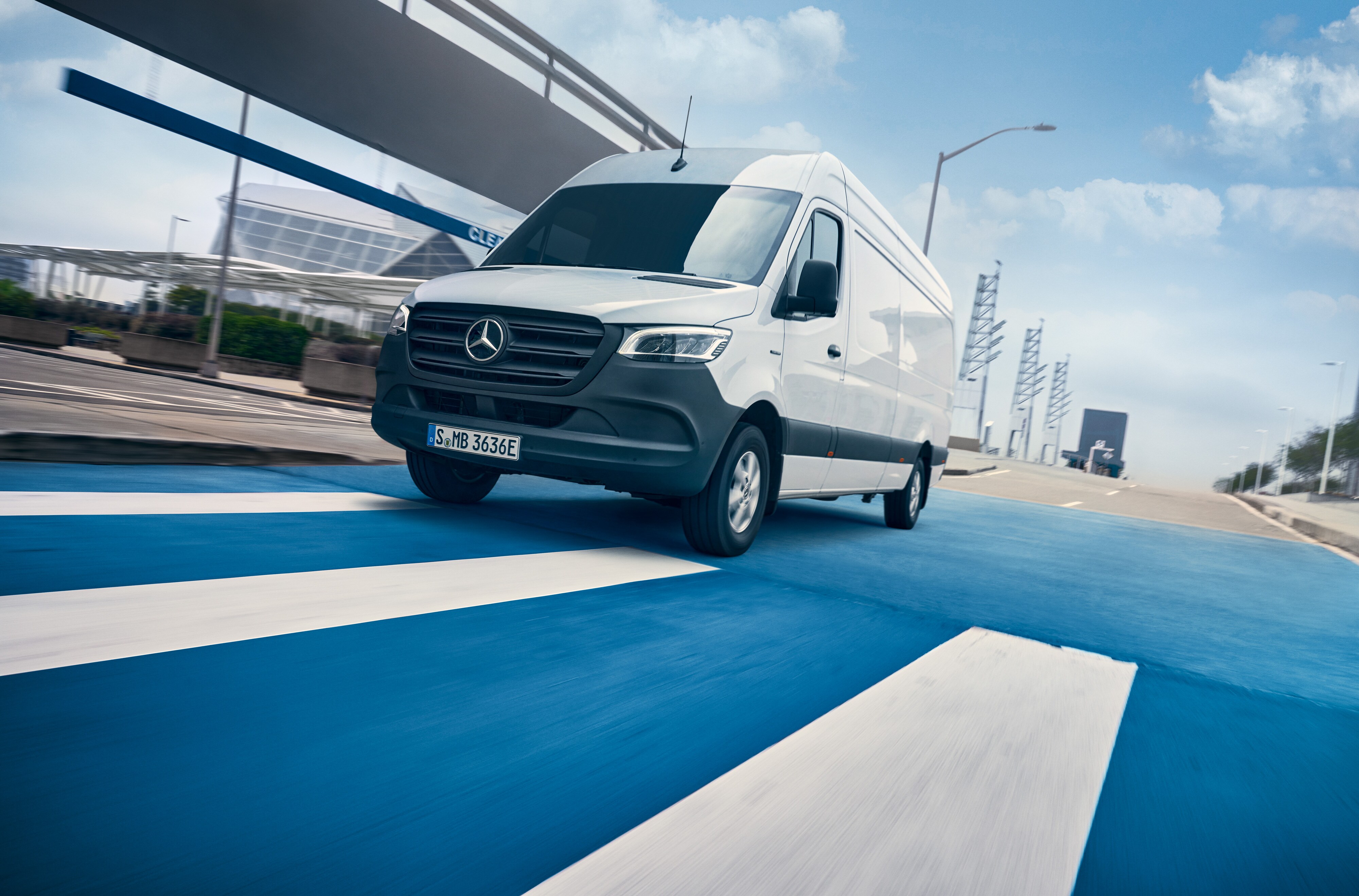 Mercedes-Benz | Van ServiceCare | Servicepaket En vit Mercedes-Benz Sprinter kör på en väg genom en stad.