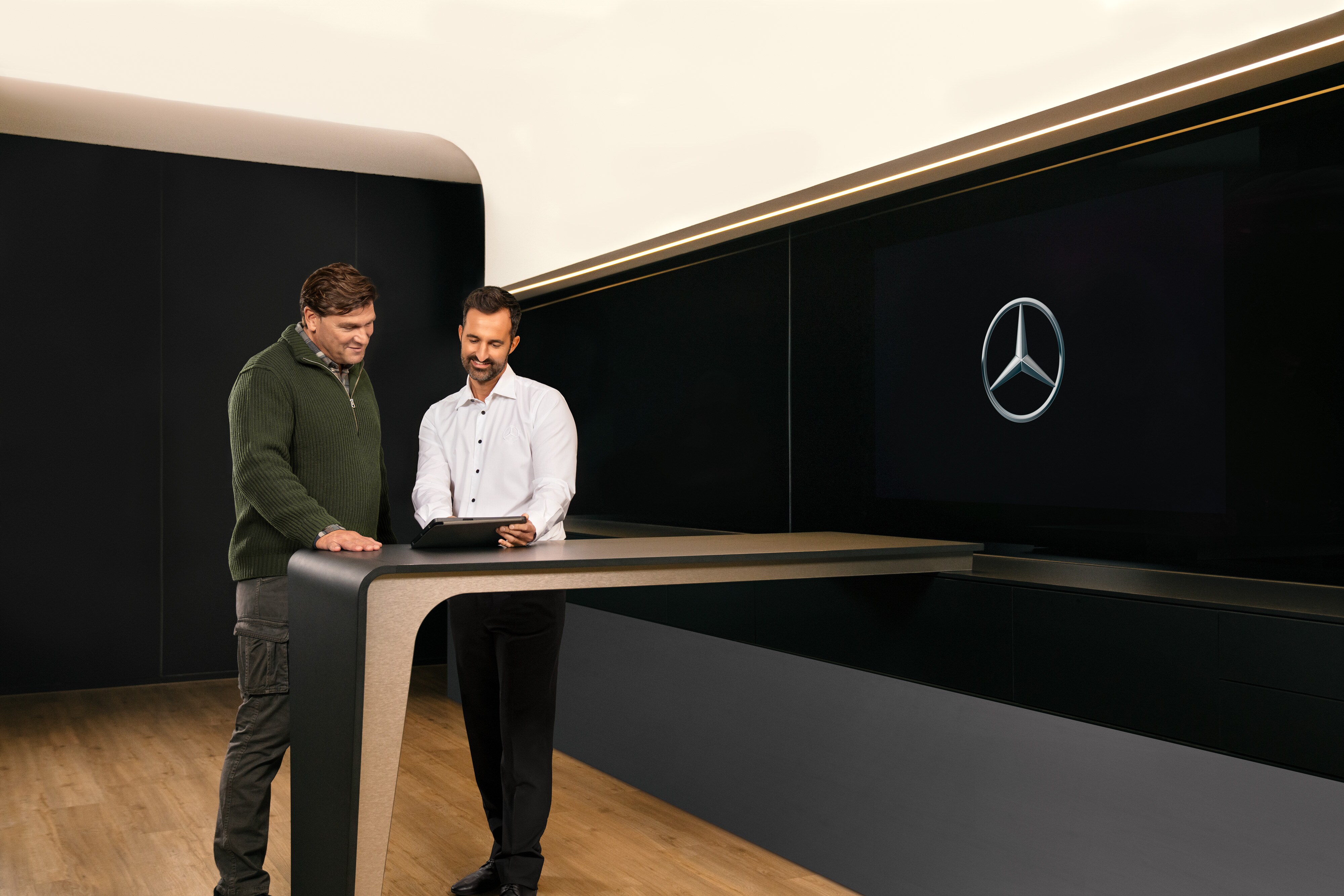 Mercedes-Benz | Översikt över tjänster | ServiceCare Två män diskuterar service för nkommersiella fordon från Mercedes-Benz över en surfplatta.